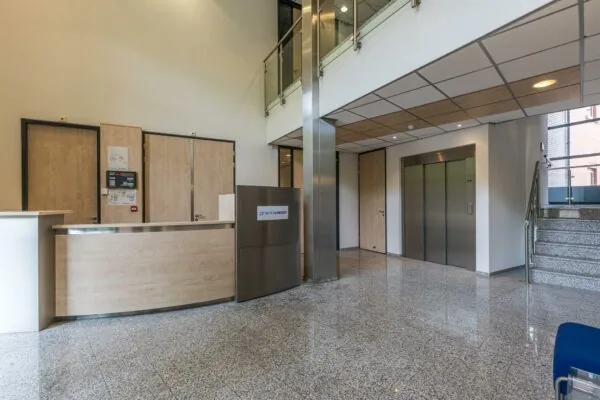 Moderne ontvangsthal met balie, lift, trap en het logo van GrandVision aan de Laan Blusse van Oud Alblas.